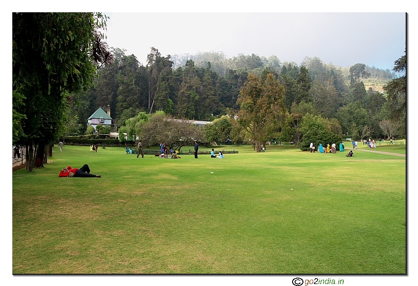 Person sleeping while others enjoy the scene in Botanical Garden, Ooty