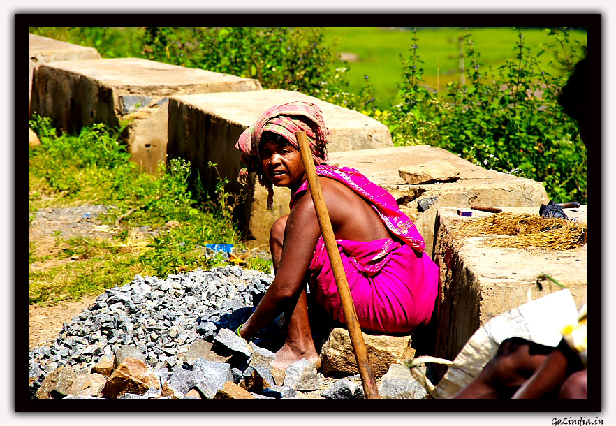 a lady sitting and breaking the pebbles for her daily earnings
