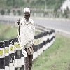 old aged villager walking alone beside the road