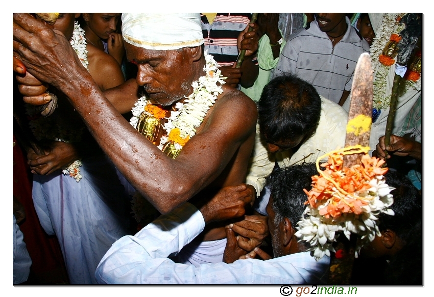 Needle piercing the skin at the waist of the priest during the festival
