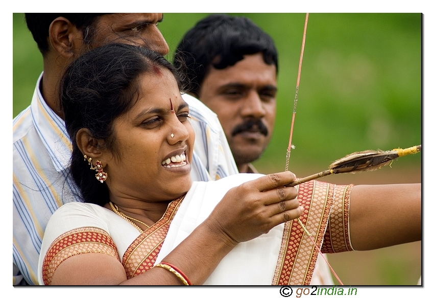 Lady aiming at a target with bow and an arrow