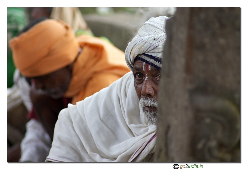 An old man looking curiously beging a pillar