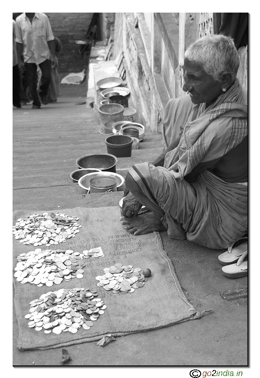 Old woman with lot of coins paisa and empty bowls of beggers
