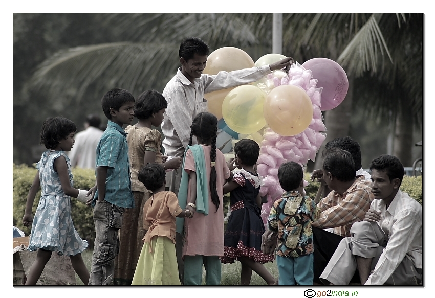 Balloon vendor in park children purchasing