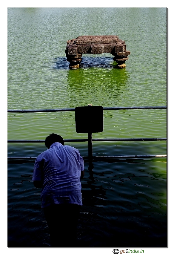 person washing face before entering temple at sacred pond