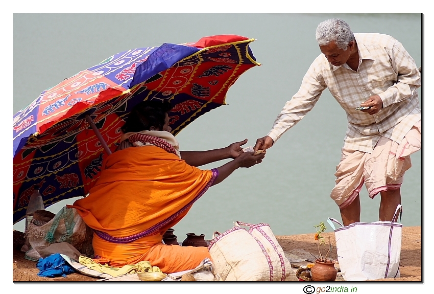 of a man offering money to preist near a lake at Bhubaneshwar Lingaraj temple