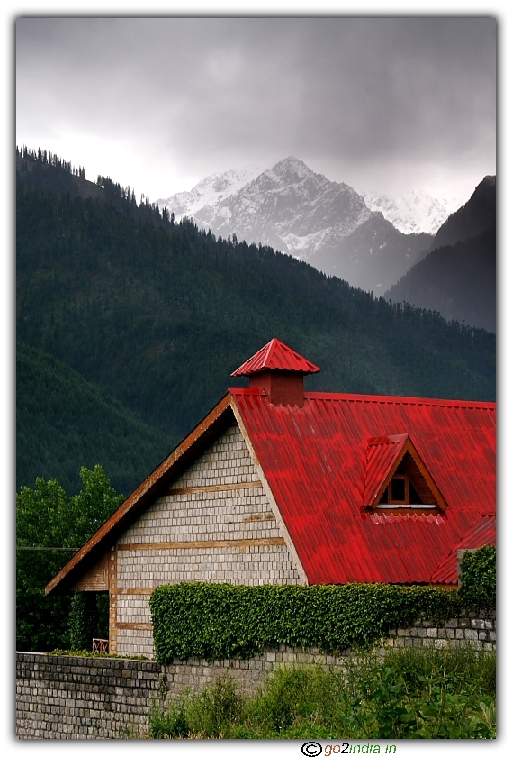 House with red color roof, ice covered hills at the back