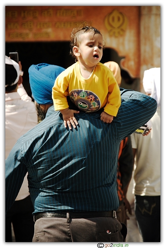 kid feeling uncomfortable on father shoulder near Gurdwara of Manikaran