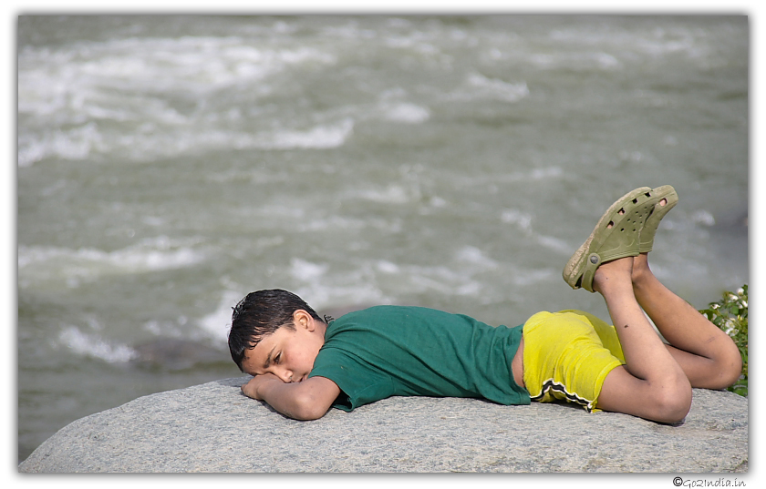 Boy laying upside down on a rock near Beas river